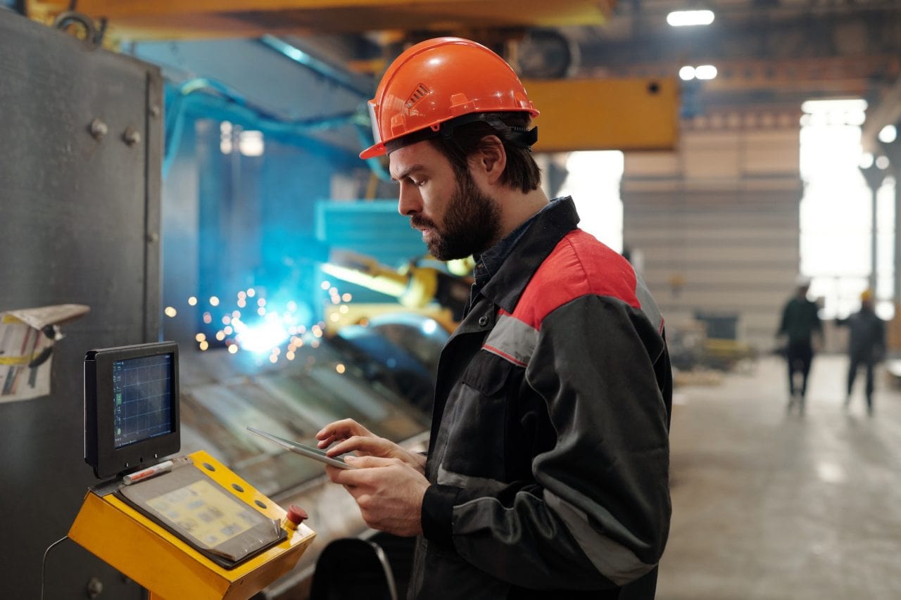 side view of young engineer in workwear using digital tablet